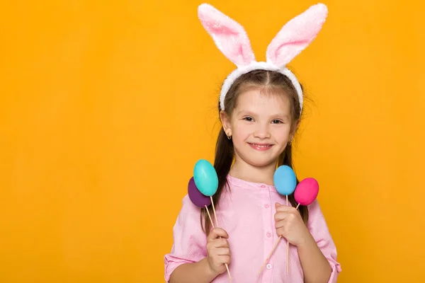 Ładna dziewczynka z Easter bunny uszy gospodarstwa kolorowych jaj — Zdjęcie stockowe