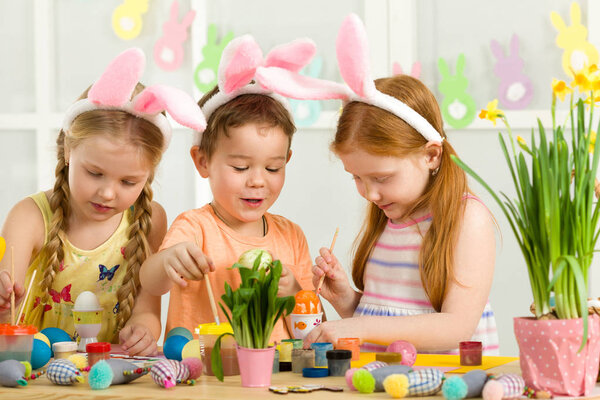 милые дети рисуют пасхальные яйца дома
.