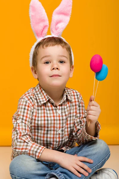 Dítě chlapec s velikonoční zajíček uši drží barevné vejce — Stock fotografie