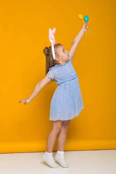 Menina bonito com orelhas de coelho de Páscoa segurando ovos coloridos — Fotografia de Stock