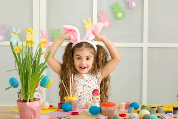 Litet barn flicka med Easter bunny öron måla påskägg hemma. — Stockfoto