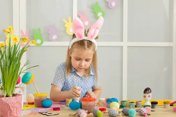 Bambina bambina con le orecchie di coniglio di Pasqua pittura uova di Pasqua a casa . — Foto Stock