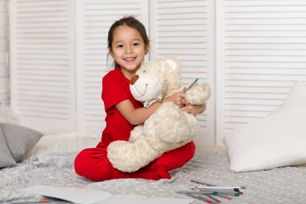 little child girl draws with pencils at home