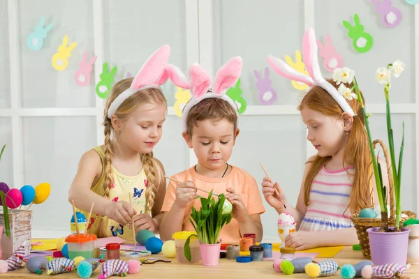 Crianças bonitos pintando ovos de Páscoa em casa . — Fotografia de Stock
