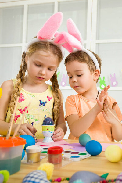 милые дети рисуют пасхальные яйца дома
.