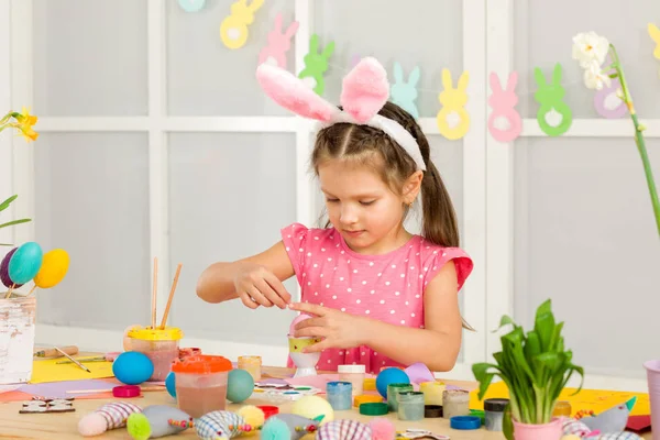 Bambina bambina con le orecchie di coniglio di Pasqua pittura uova di Pasqua a casa . — Foto Stock