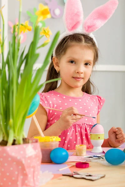 Małe dziecko dziewczyna z Easter bunny uszy pisanki w domu. — Zdjęcie stockowe