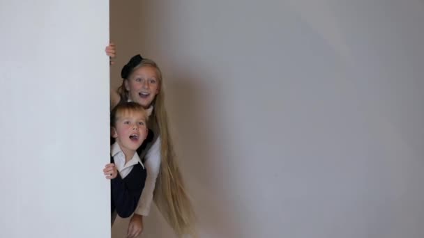 Kinder blicken hinter weißem Blanko-Plakat hervor. — Stockvideo