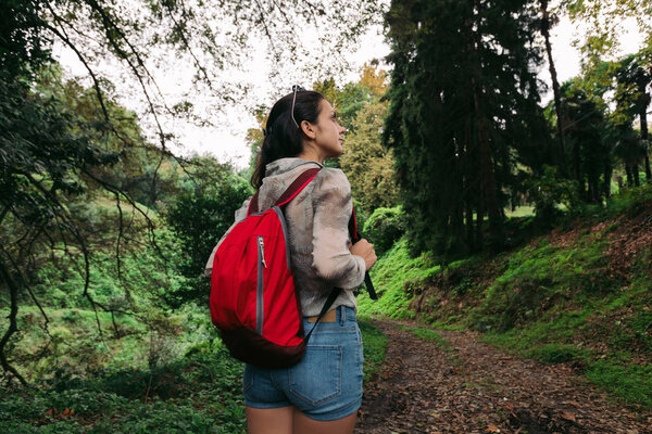 woman with backpack walking in the forest