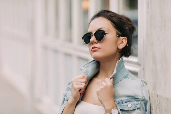 Belle femme en lunettes de soleil et robe blanche se promène dans les rues de la ville par une journée ensoleillée — Photo