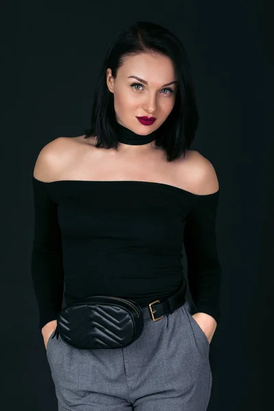 Žena v černém svetru s kabelkou pózuje ve studiu — Stock fotografie
