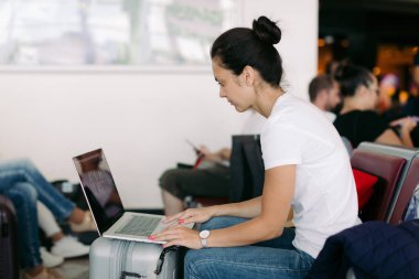 havaalanında dizüstü bilgisayar kullanarak kadın yolcu