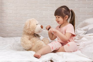 Sevimli çocuk kız oyuncak ayı ile doktor oynuyor