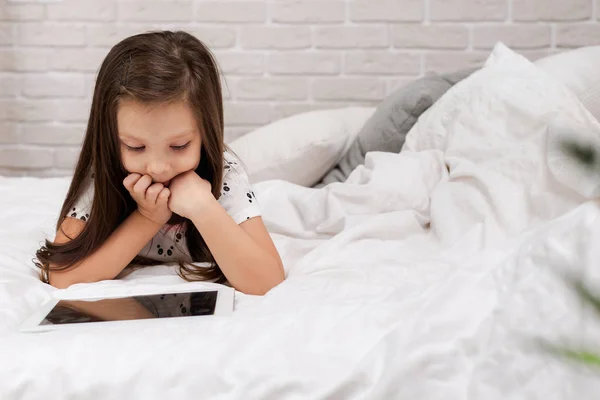 Kislány hazudik az ágyban Használja a digitális tabletta. — Stock Fotó