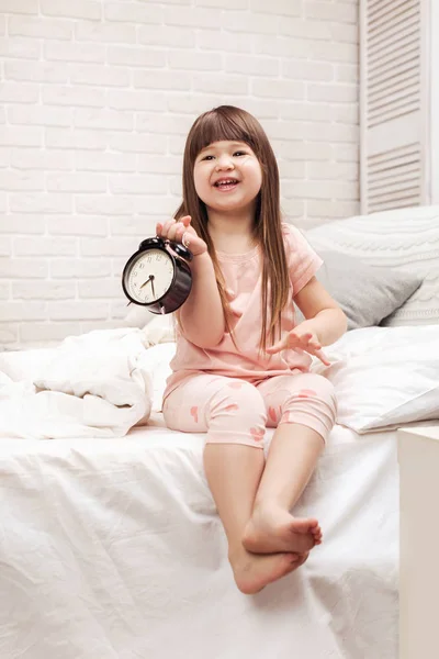 Petite fille enfant en pyjama avec horloge — Photo