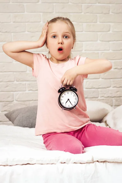 Menina criança em pijama com relógio — Fotografia de Stock