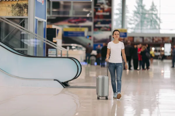 Junge Frau läuft mit Koffer in Flughafen — Stockfoto