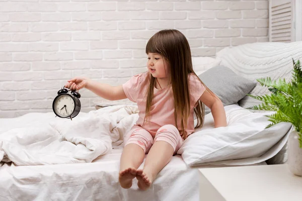 시계와 잠옷에 어린 아이 소녀 — 스톡 사진