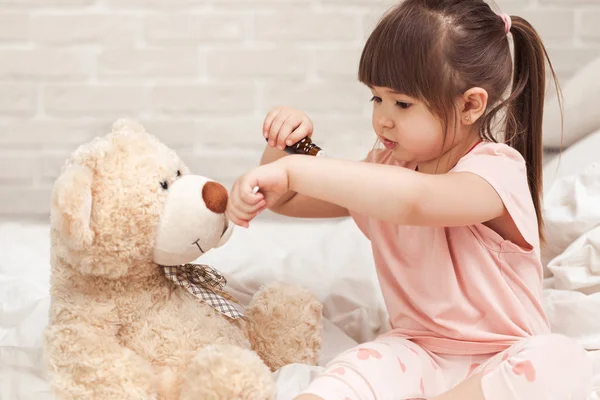 Niedliches Mädchen spielt Arzt mit Teddybär — Stockfoto