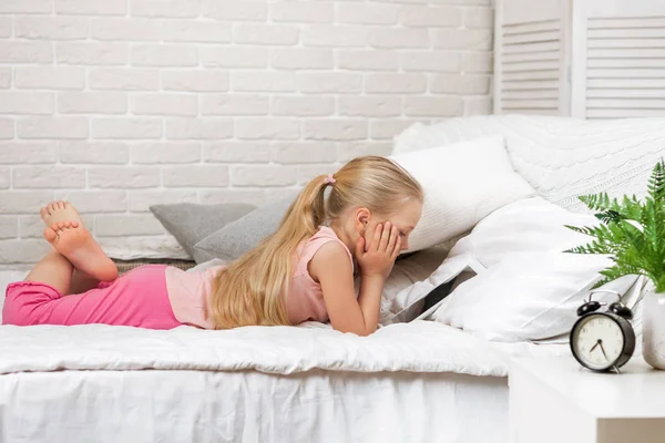 Menina minúscula mente na cama usa tablet digital. — Fotografia de Stock