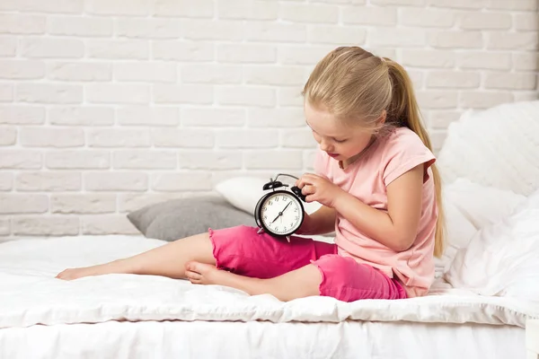Little child girl in pyjamas with clock — Stock Photo, Image