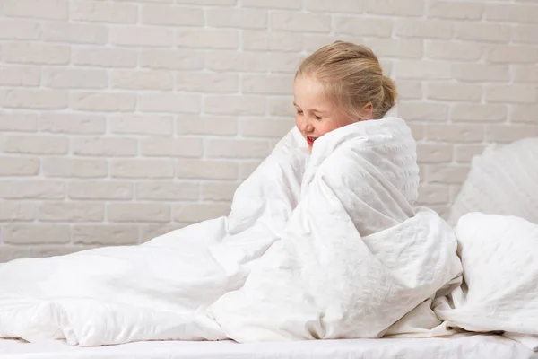 Menina criança em cobertor sentado na cama — Fotografia de Stock