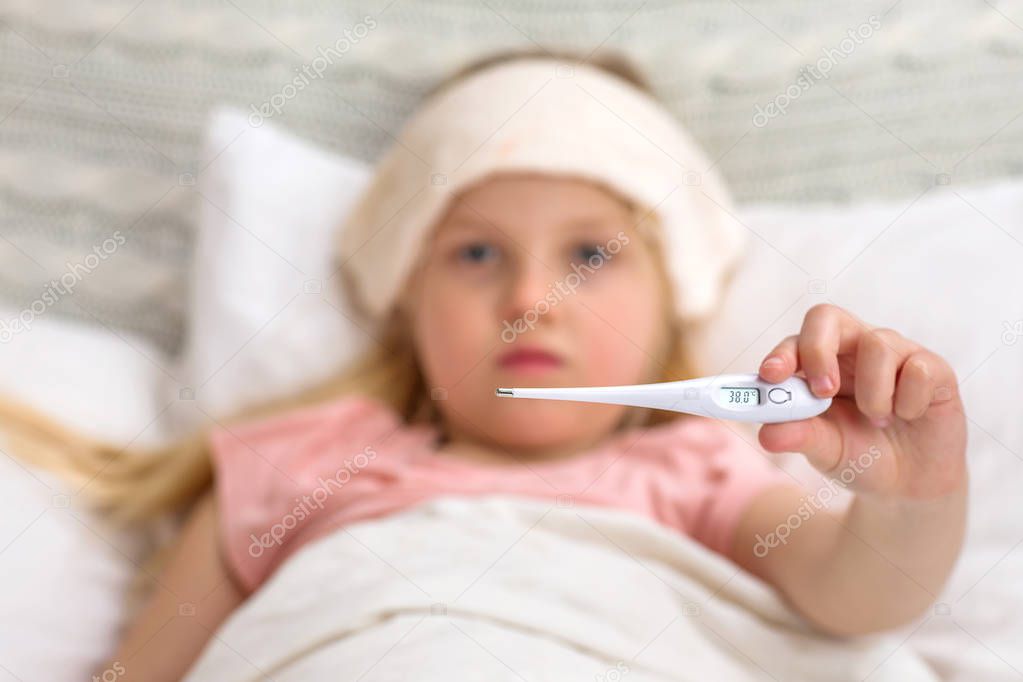 Sick little child girl lying in bed with thermometer.
