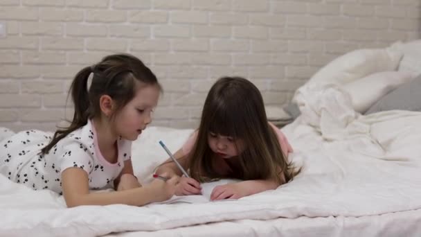 Niños haciendo dibujos mientras están acostados en la cama . — Vídeos de Stock