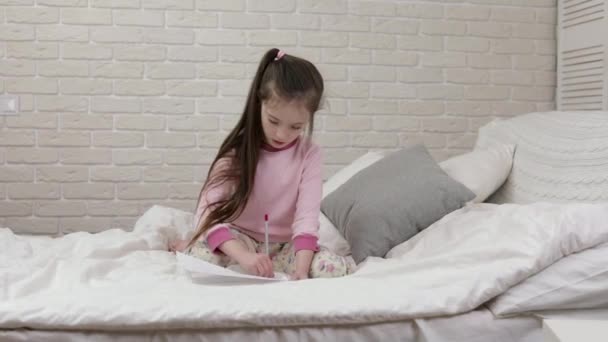 Bonito menina desenho imagens enquanto deitado na cama . — Vídeo de Stock