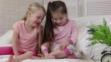 çocuklar yatakta yatarken resim çizer.