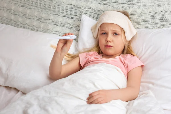 Sick little child girl lying in bed with thermometer. — Stock Photo, Image