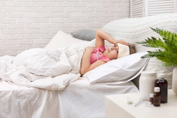 Ziek meisje in bed liggen met thermometer — Stockfoto