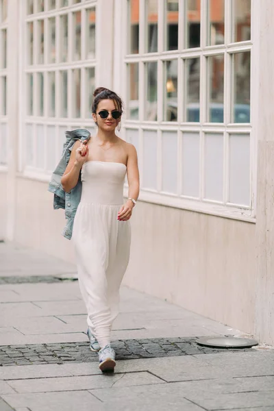 Femeie atractivă în ochelari de soare și rochie albă merge pe străzile orașului într-o zi însorită — Fotografie, imagine de stoc