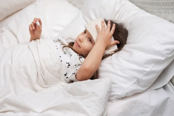 Sick little child girl lying in bed with thermometer. — Stock Photo, Image