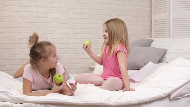 Duas crianças pequenas meninas comem maçãs frescas verdes — Vídeo de Stock