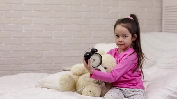 Little child girl sets the alarm in bed — Stock Video