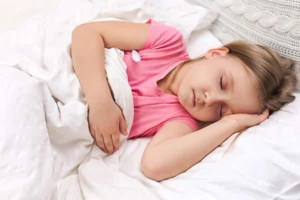 生病的小女孩躺在床上用温度计 — 图库照片
