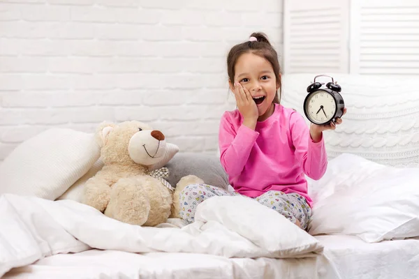 Petite fille en pyjama avec horloge — Photo