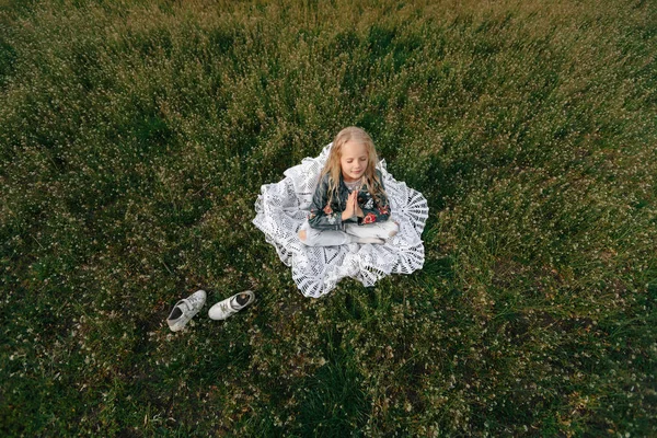 Kleines Mädchen sitzt meditierend auf grünem Rasen — Stockfoto