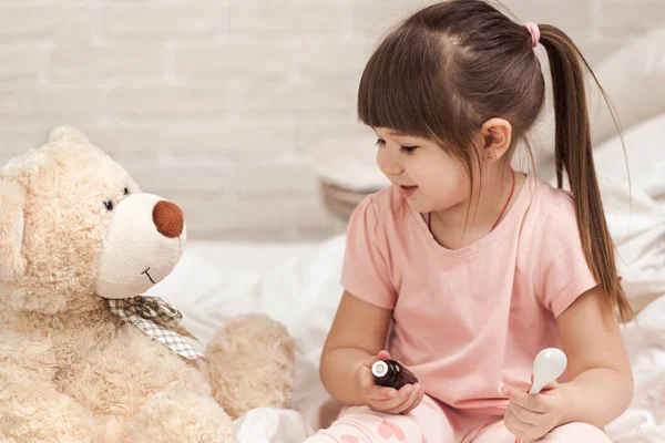 Cute child girl playing doctor with teddy bear — Stock Photo, Image