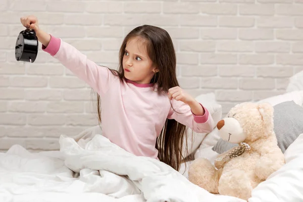 Kis gyermek lány pizsama órával — Stock Fotó