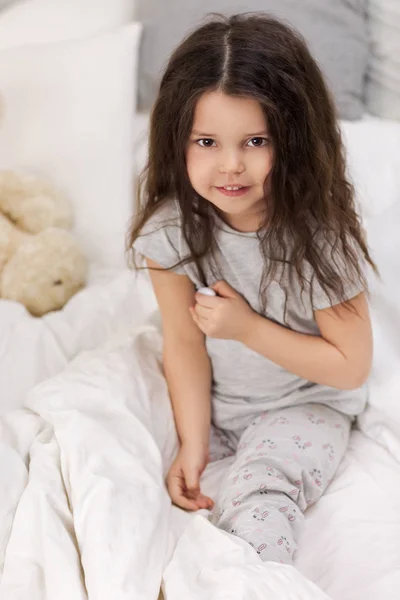 Menina doente deitada na cama com termômetro — Fotografia de Stock