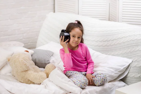 Маленькая девочка в пижаме с часами — стоковое фото