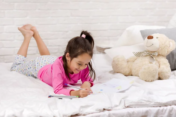 Yatakta yatarken sevimli küçük kız çizim resimleri — Stok fotoğraf
