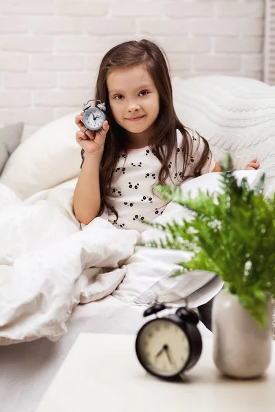 Menina criança em pijama com relógio — Fotografia de Stock