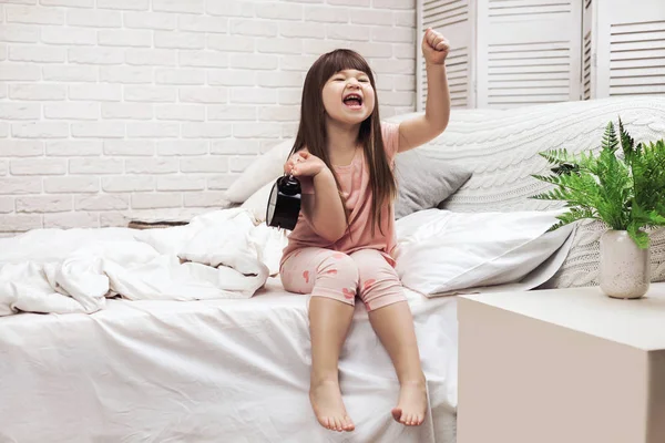 little child girl in pyjamas with clock