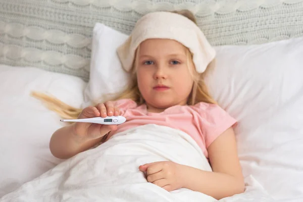 Sick little child girl lying in bed with thermometer. — Stock Photo, Image