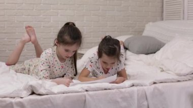 çocuklar yatakta yatarken resim çizer.