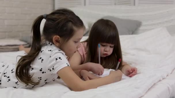 Niños haciendo dibujos mientras están acostados en la cama . — Vídeos de Stock