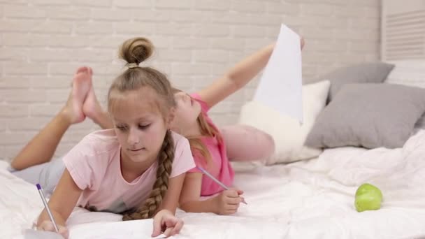 Kids drawing pictures while lying on bed. — Stock Video